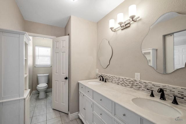 bathroom featuring toilet, a sink, decorative backsplash, and double vanity