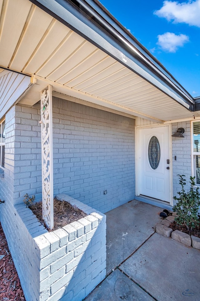 view of exterior entry featuring brick siding