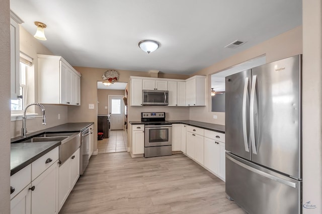 kitchen with dark countertops, visible vents, appliances with stainless steel finishes, and a sink