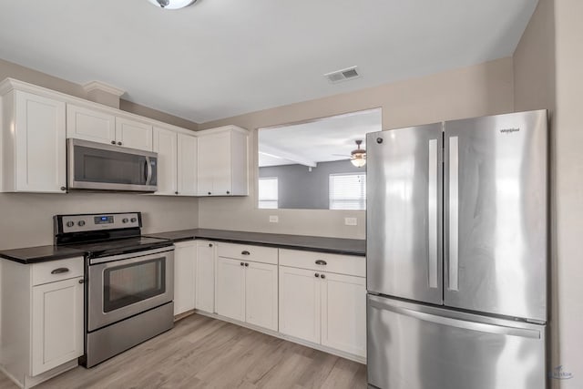 kitchen featuring light wood-type flooring, appliances with stainless steel finishes, dark countertops, and visible vents