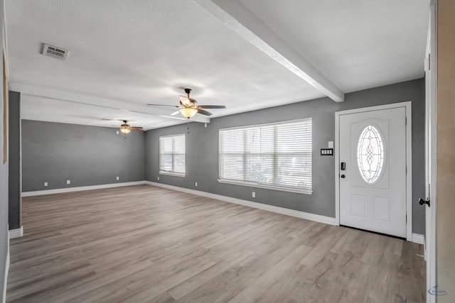 foyer featuring light wood-style floors, visible vents, a textured ceiling, and baseboards