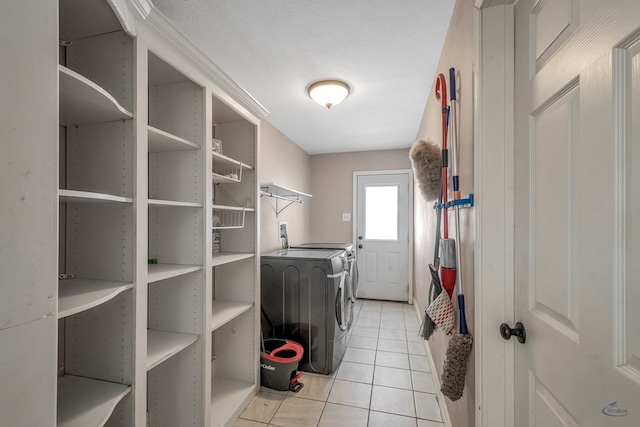 clothes washing area featuring a textured ceiling, laundry area, light tile patterned flooring, and washing machine and dryer