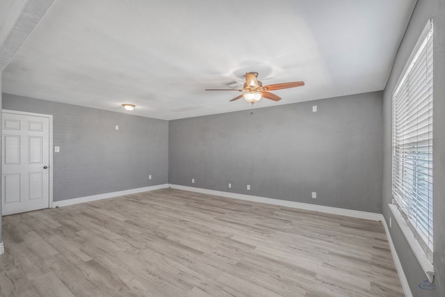 empty room featuring light wood finished floors, a ceiling fan, and baseboards