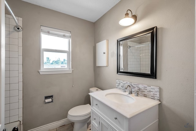 full bathroom with toilet, vanity, baseboards, a shower, and decorative backsplash