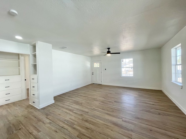 unfurnished living room with ceiling fan, light hardwood / wood-style floors, and a textured ceiling