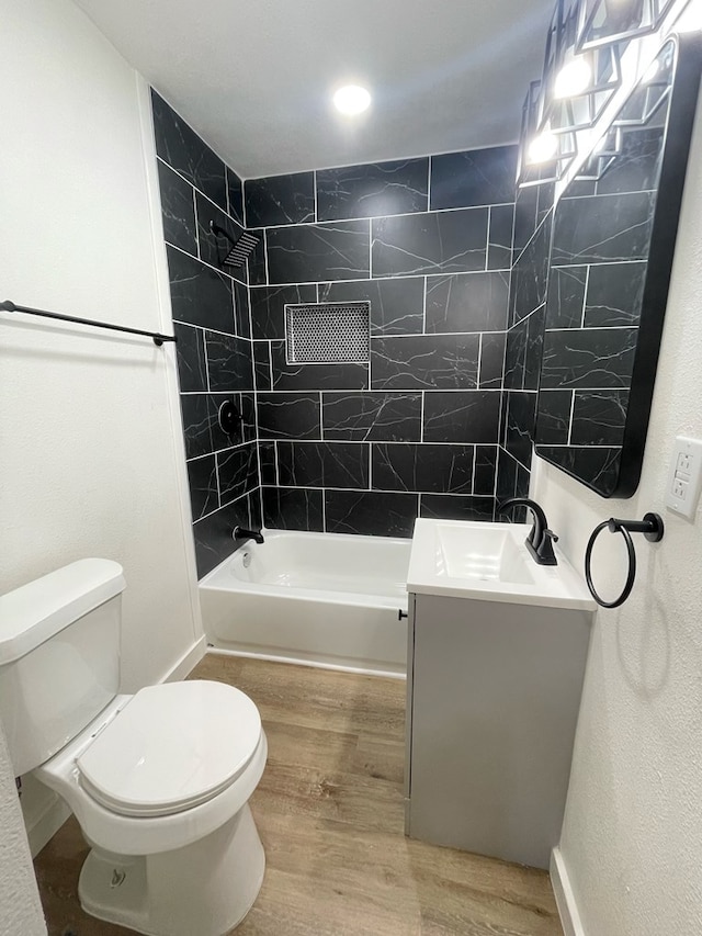 full bathroom with hardwood / wood-style flooring, vanity, toilet, and tiled shower / bath