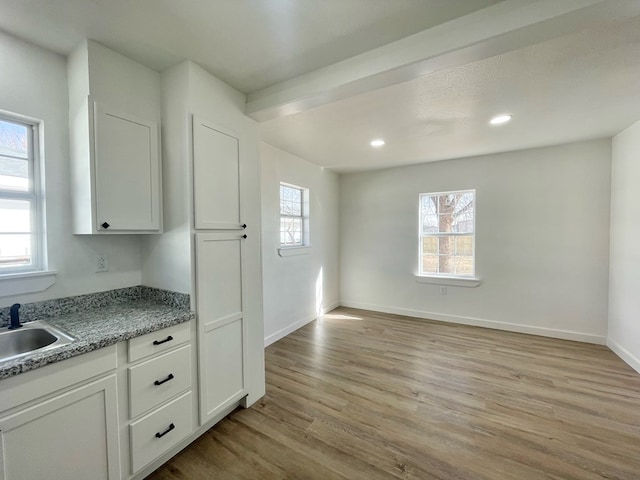 kitchen featuring light hardwood / wood-style floors, white cabinetry, plenty of natural light, and sink