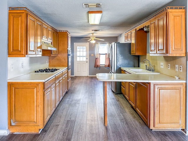 kitchen with white gas stovetop, light countertops, visible vents, a sink, and under cabinet range hood