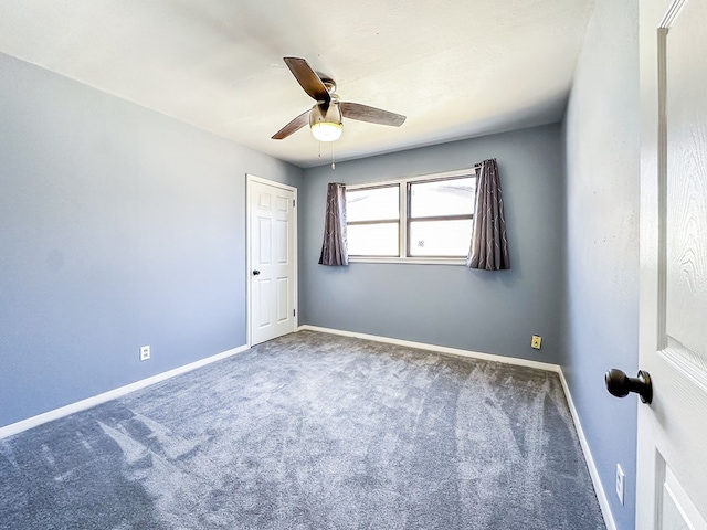 carpeted spare room featuring ceiling fan and baseboards