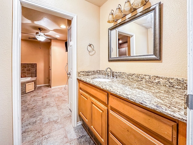 full bathroom featuring a ceiling fan, a tub, vanity, and baseboards