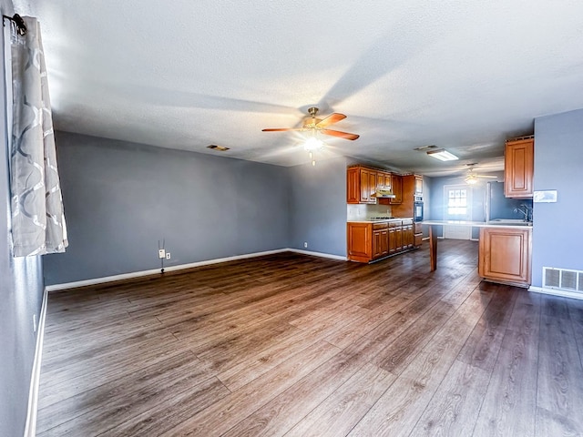 interior space with dark wood-style flooring, a sink, visible vents, baseboards, and a ceiling fan