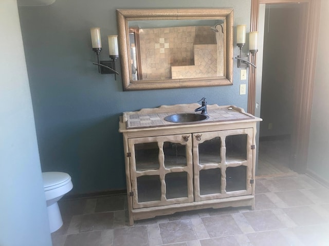 full bathroom with baseboards, vanity, and toilet