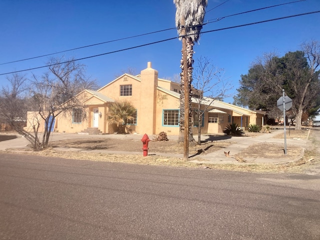 view of front of house with a chimney and stucco siding