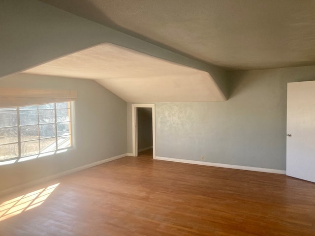 bonus room with vaulted ceiling, a textured ceiling, baseboards, and wood finished floors