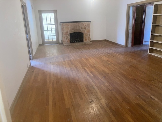 unfurnished living room featuring a stone fireplace and hardwood / wood-style floors