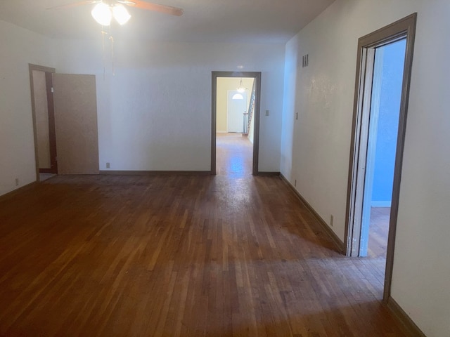 empty room with baseboards, ceiling fan, visible vents, and wood finished floors