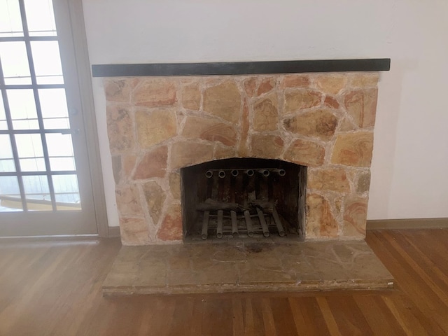 room details with a stone fireplace, baseboards, and wood finished floors