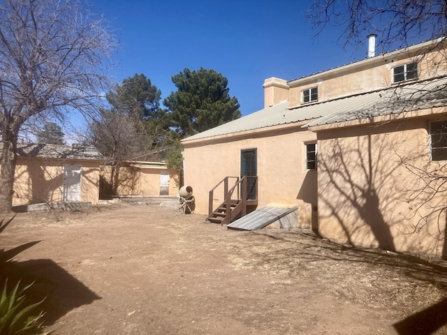 back of house with metal roof and stucco siding