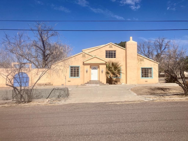 view of front of home featuring a chimney and stucco siding