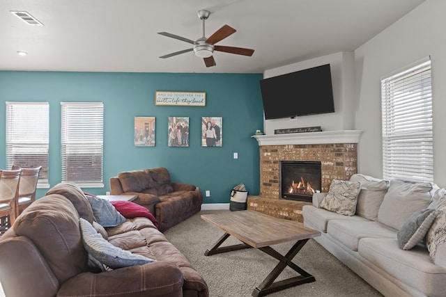 carpeted living room with a brick fireplace and ceiling fan