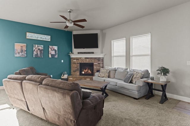 living room with carpet flooring, ceiling fan, and a stone fireplace