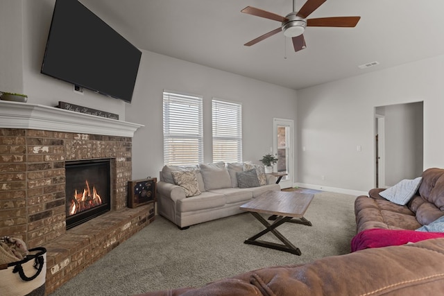 living room with a brick fireplace, ceiling fan, and carpet flooring