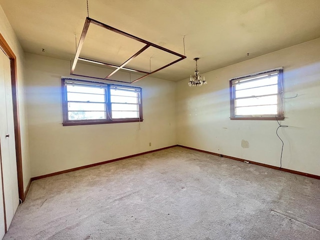 empty room with carpet floors and a notable chandelier