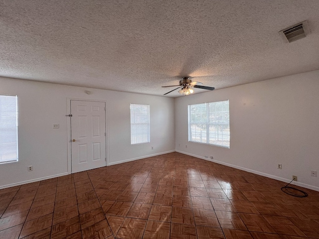 unfurnished room with dark parquet flooring, ceiling fan, and a healthy amount of sunlight