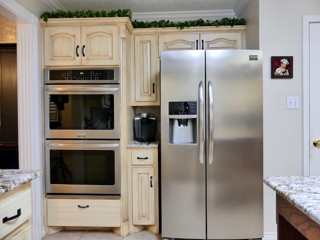 kitchen with appliances with stainless steel finishes, ornamental molding, light brown cabinets, a textured ceiling, and light stone countertops