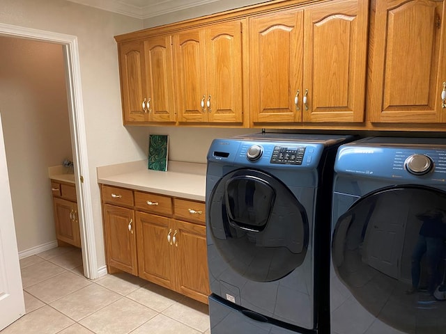 clothes washing area with cabinet space, light tile patterned floors, baseboards, ornamental molding, and washing machine and dryer