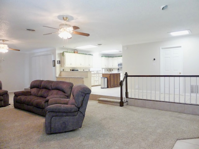 living area featuring visible vents, a ceiling fan, and light colored carpet