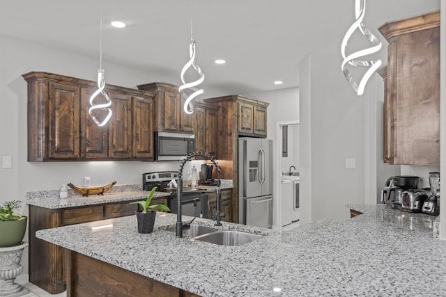 kitchen with pendant lighting, appliances with stainless steel finishes, a sink, dark brown cabinets, and a peninsula