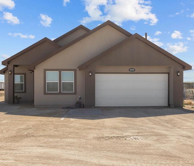 ranch-style house featuring driveway, an attached garage, and stucco siding