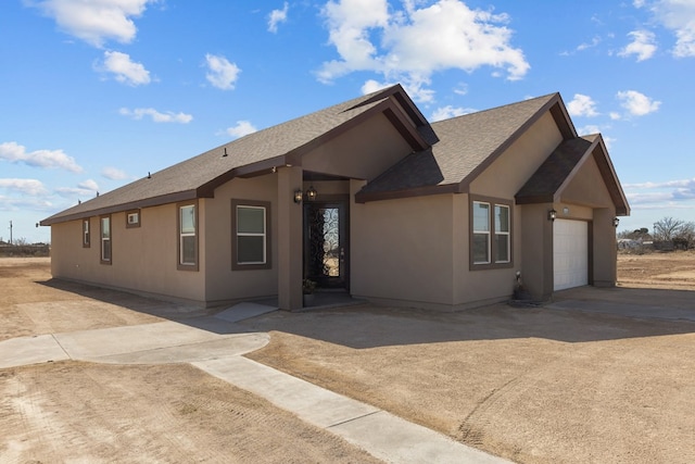 ranch-style house featuring a garage, concrete driveway, a shingled roof, and stucco siding