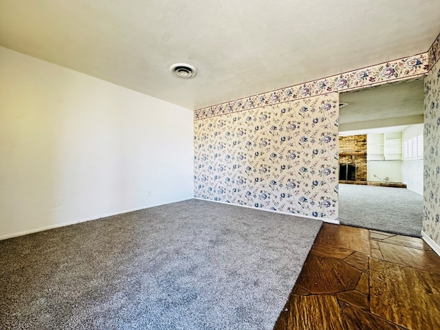 carpeted empty room featuring a fireplace, a textured ceiling, and built in features