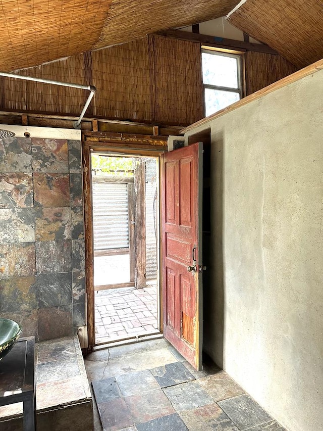 doorway to outside featuring lofted ceiling and stone tile floors