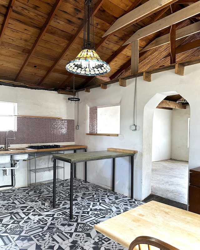 kitchen featuring arched walkways, wood ceiling, a sink, and lofted ceiling with beams