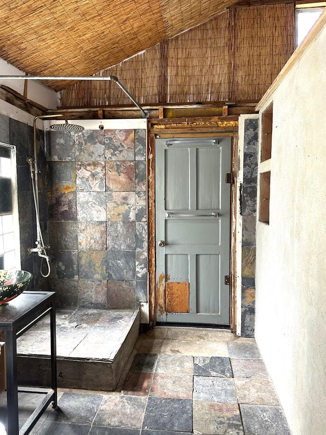 interior space featuring lofted ceiling, wooden ceiling, and stone tile floors