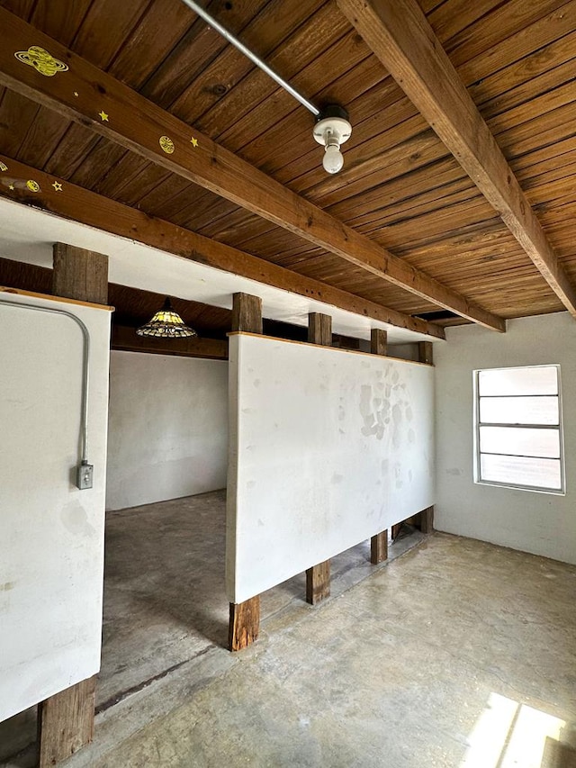 empty room with wood ceiling, concrete flooring, and beamed ceiling