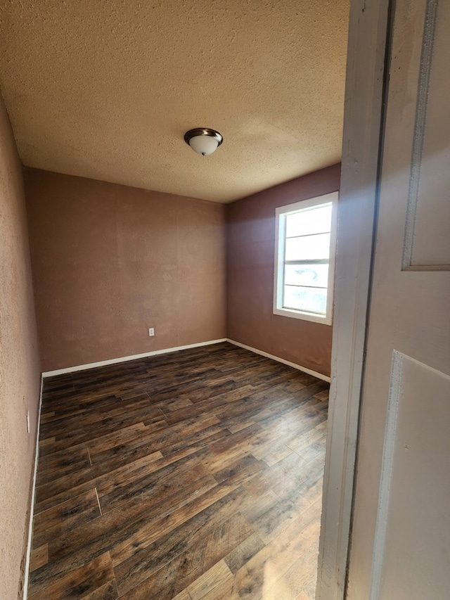 spare room with dark hardwood / wood-style floors and a textured ceiling