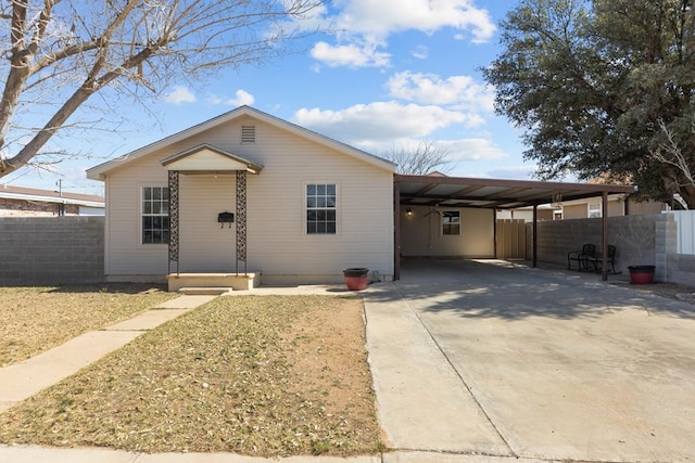 ranch-style house with an attached carport, concrete driveway, and fence