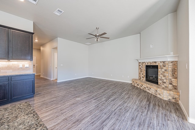 unfurnished living room with a fireplace, dark hardwood / wood-style floors, and ceiling fan