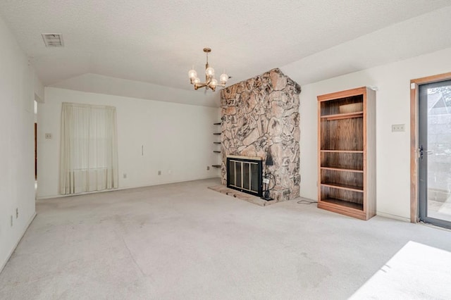 unfurnished living room with a textured ceiling, vaulted ceiling, an inviting chandelier, carpet floors, and a stone fireplace