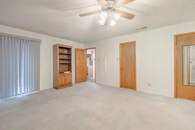 unfurnished bedroom with ceiling fan, light colored carpet, and a textured ceiling