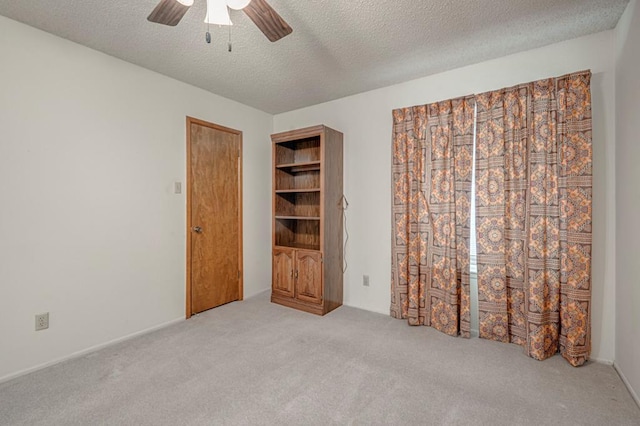 unfurnished bedroom with ceiling fan, a textured ceiling, and light carpet