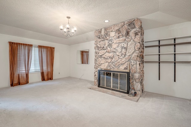 unfurnished living room featuring a textured ceiling, an inviting chandelier, a stone fireplace, and carpet floors