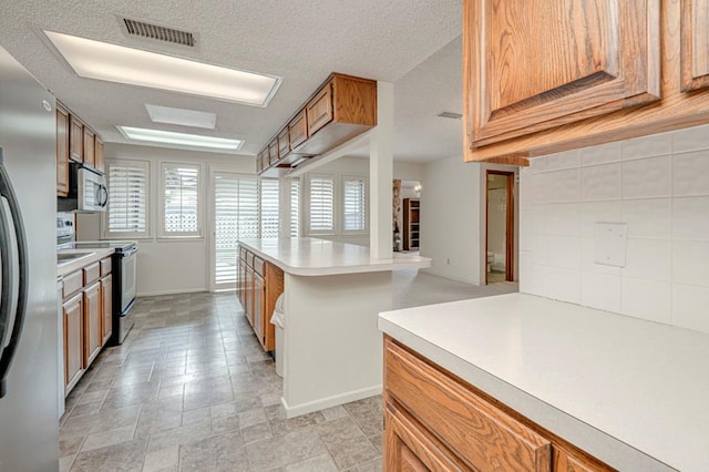 kitchen featuring kitchen peninsula, appliances with stainless steel finishes, and a textured ceiling