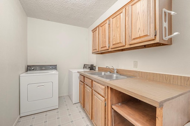 washroom with washer and clothes dryer, cabinets, a textured ceiling, and sink