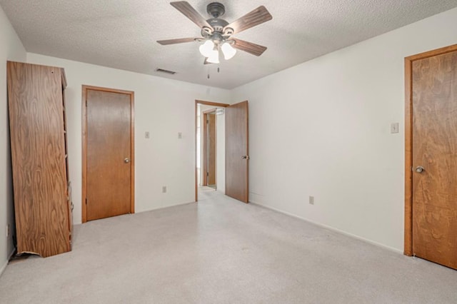 unfurnished bedroom featuring ceiling fan, light colored carpet, and a textured ceiling