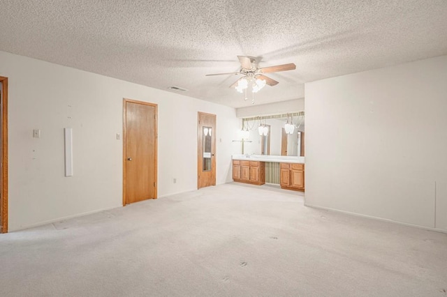 unfurnished living room with light carpet, a textured ceiling, and ceiling fan